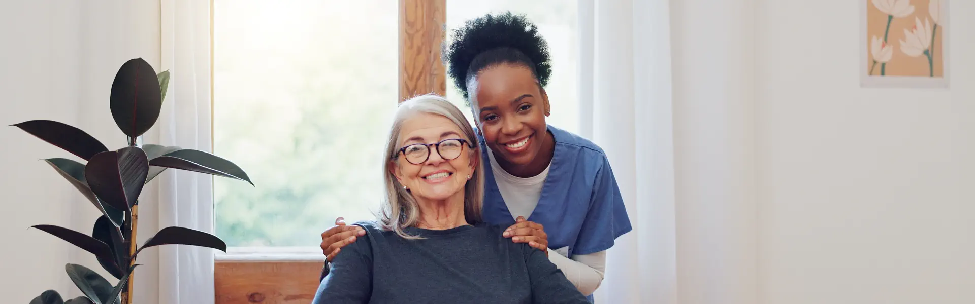 A female caregiver putting her hands on the shoulders of a senior woman sitting