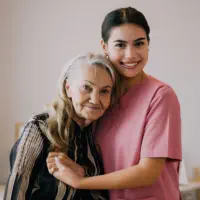 A senior woman hugging the female caregiver