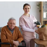 A senior man sitting on and a female caregiver preparing the foods in the bag
