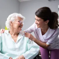 A female caregiver and a senior woman looking at each other