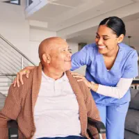 A female caregiver putting her hands on the shoulders of a senior man