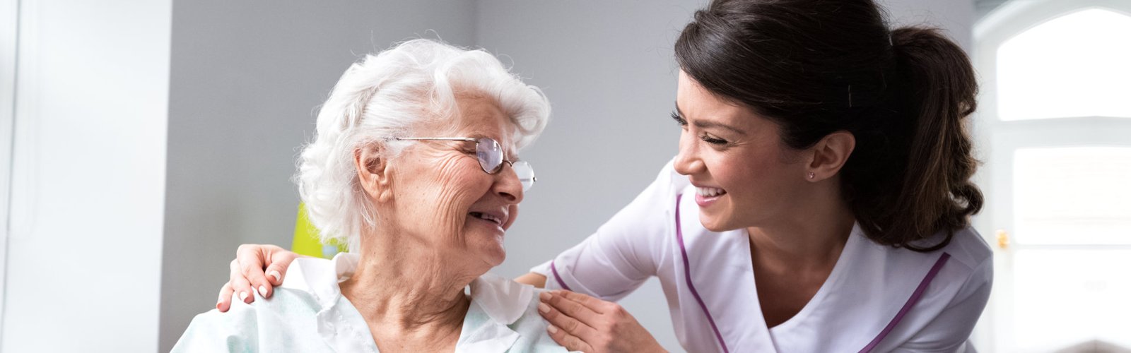 A female caregiver and a senior woman looking at each other