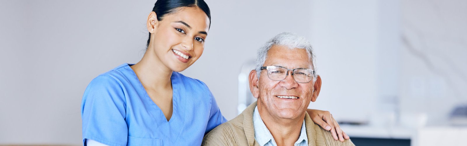 A female caregiver and a senior man smiling