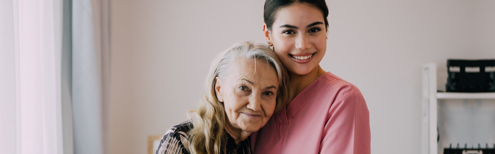 A senior woman hugging the female caregiver