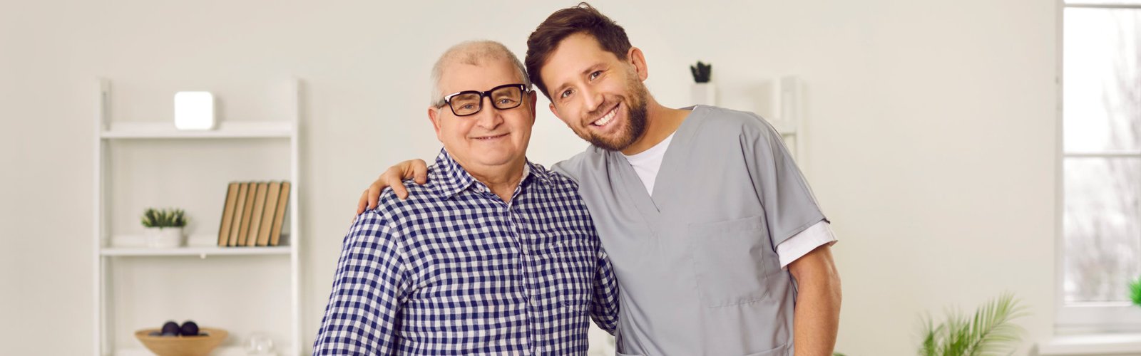 A male caregiver and a senior man smiling together