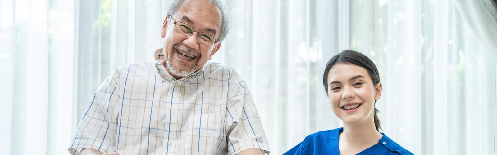 A senior man and a female caregiver smiling
